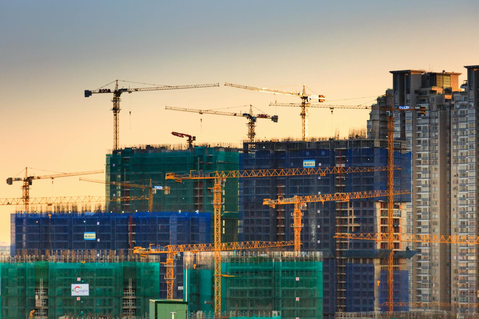 Construction cranes over a city skyline at dusk