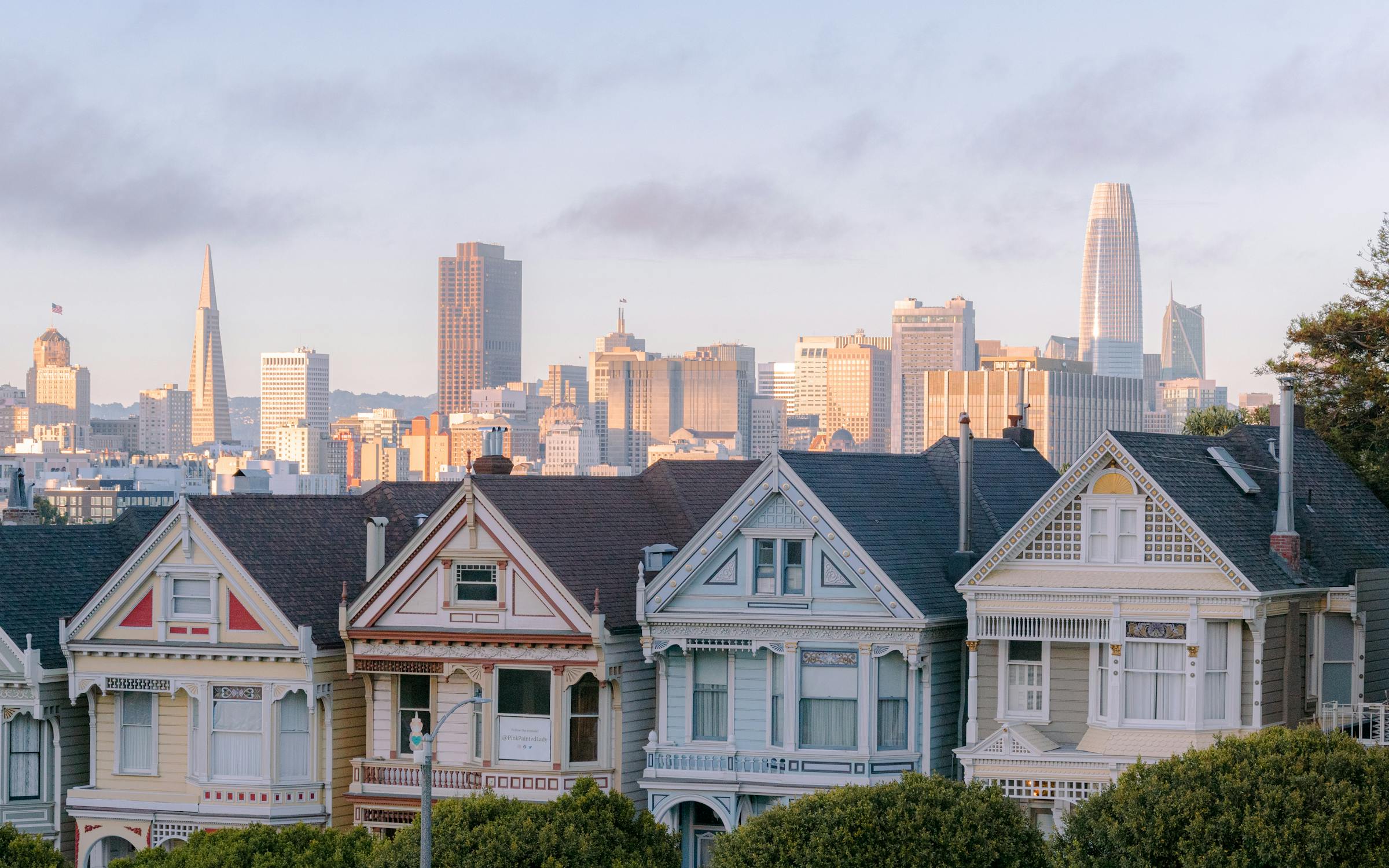 San Francisco's Painted Ladies — Victorian row houses at golden hour with the city skyline behind