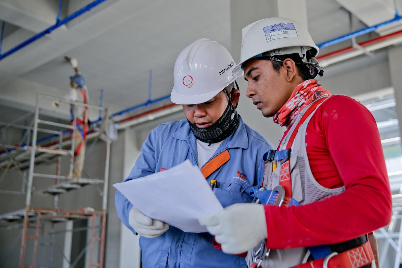 Two crew members in hard hats reviewing plans on site
